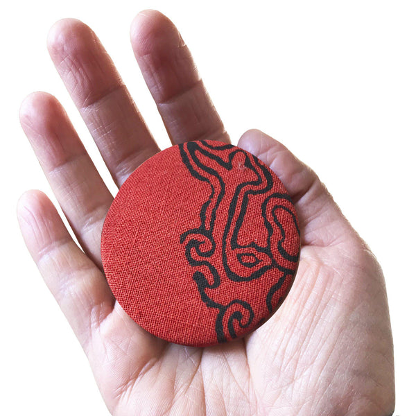 A hand holding a red cloud magnet bottle opener - Devrim Studio