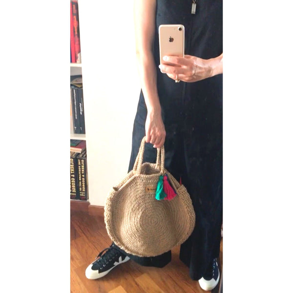 A woman holding the handwoven hemp bag with one hand posing in front of the mirror.