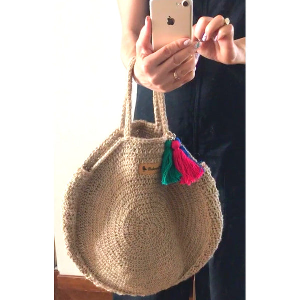 A woman holding the handwoven hemp bag with one hand posing in front of the mirror.