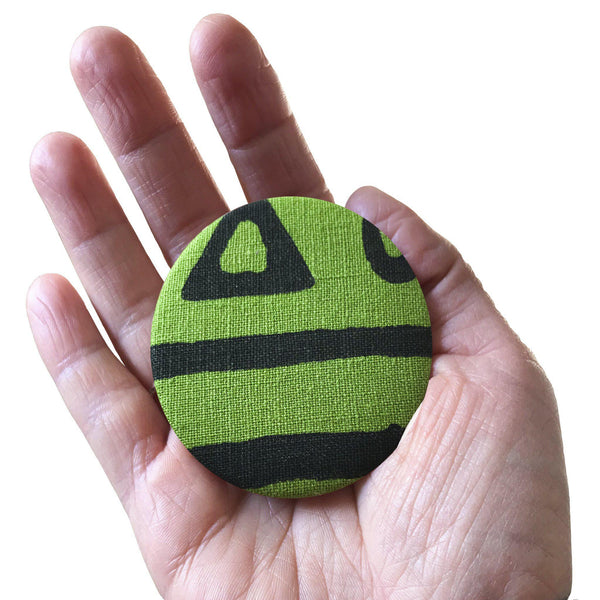 A hand holding a green 'Hazelnut' fridge magnet, bottle opener - Devrim Studio