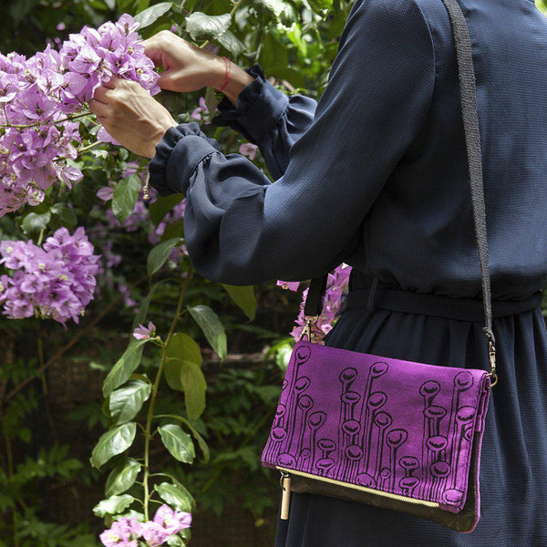 A woman wearing a purple 'Stuck to the Floor' clutch, shoulder bag -Devrim Studio