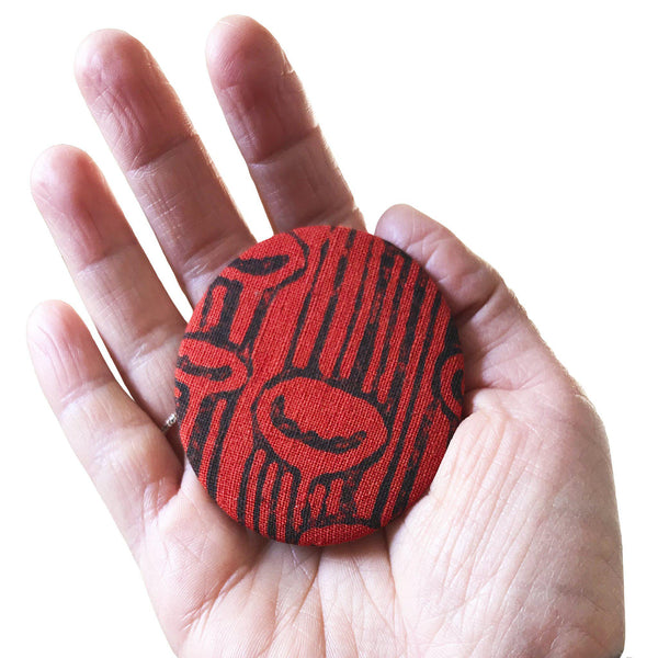 A hand holding a red 'Stuck to the floor' fridge magnet, bottle opener - Devrim Studio