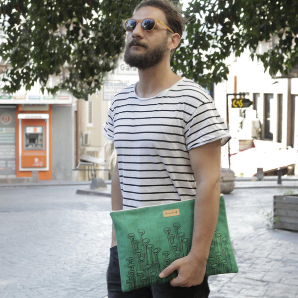 A man holding a green 'Stuck to the Floor' waxed canvas laptop sleeve, clutch - Devrim Studio
