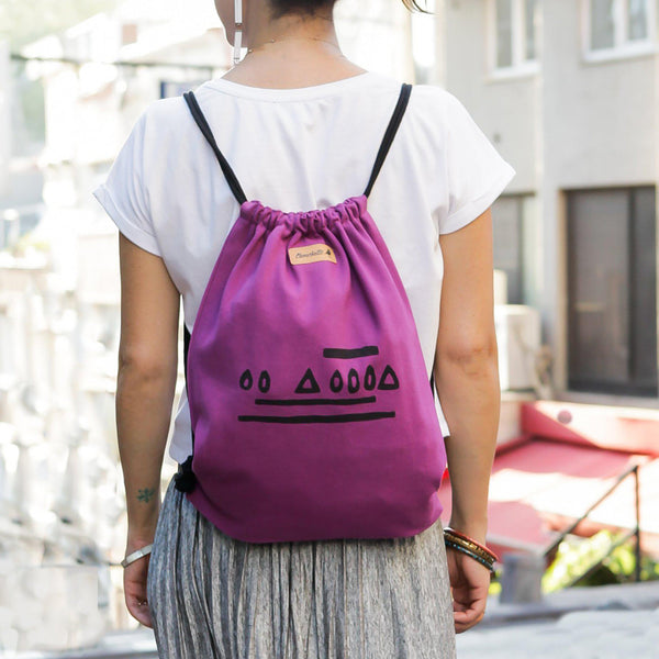 A woman wearing the purple 'Time' bucket backpack - Devrim Studio
