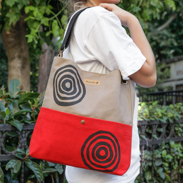 A woman wearing the beige and red 'Time' Shoulder Bag that converts into a crossbody bag - Devrim Studio