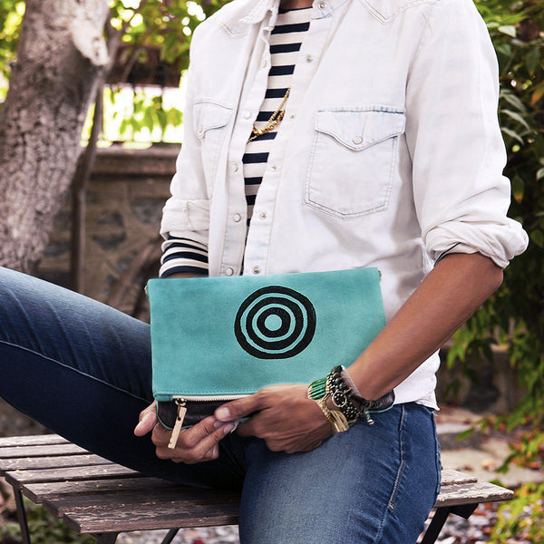 A woman holding a turquoise 'Time' shoulder bag that converts into a crossbody bag, or a fanny pack, or a clutch - Devrim Studio